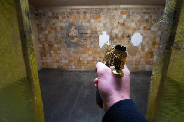 Shooting a powerful gold colored pistol at indoors shooting range.Close up photo